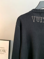 Dark knit sweater back with rhinestone logo near the shoulder