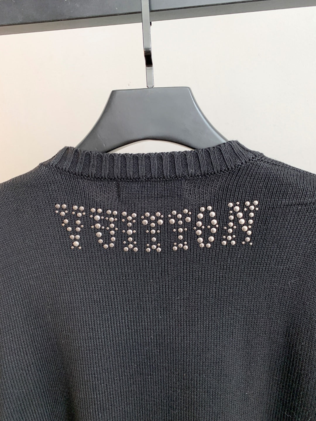 Dark knit sweater back with rhinestone logo across the upper back