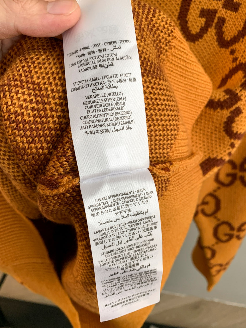 Gucci GG monogram knit sweater care label on orange knit fabric