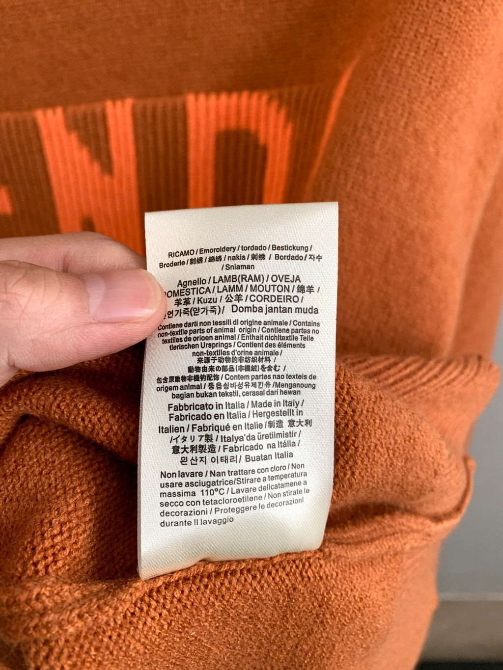 Fendi orange sweater care label tag attached to knit fabric