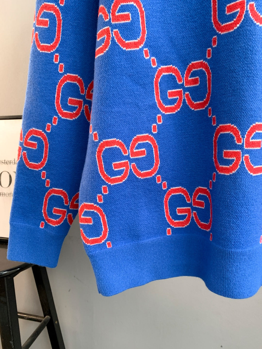 Blue knit sweater back with repeating red and white GG logo motifs