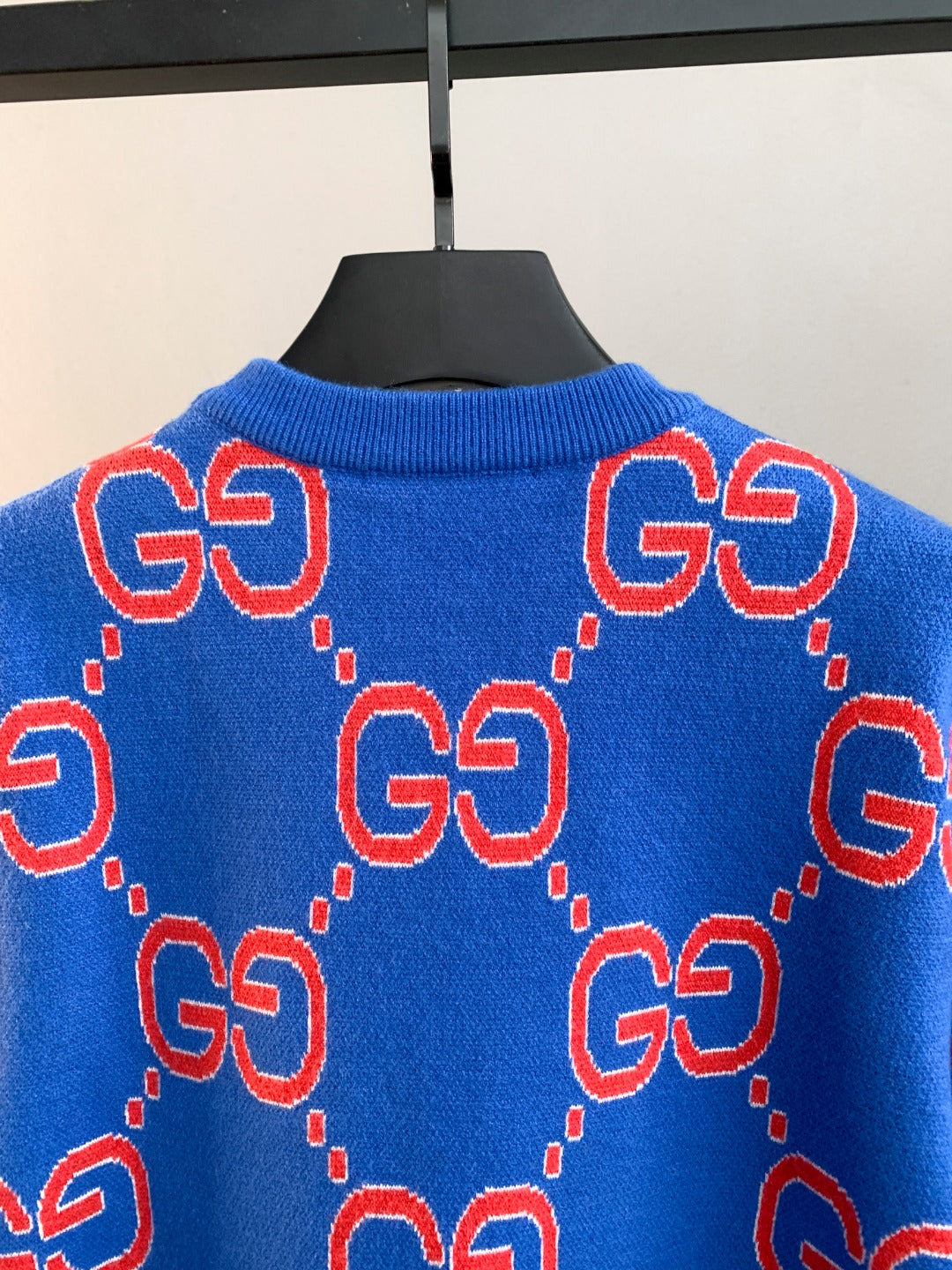 Blue knit sweater back with repeating red GG logo pattern