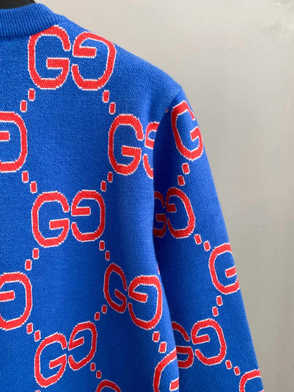 Blue knit sweater side with red GG logo motifs and dotted outlines