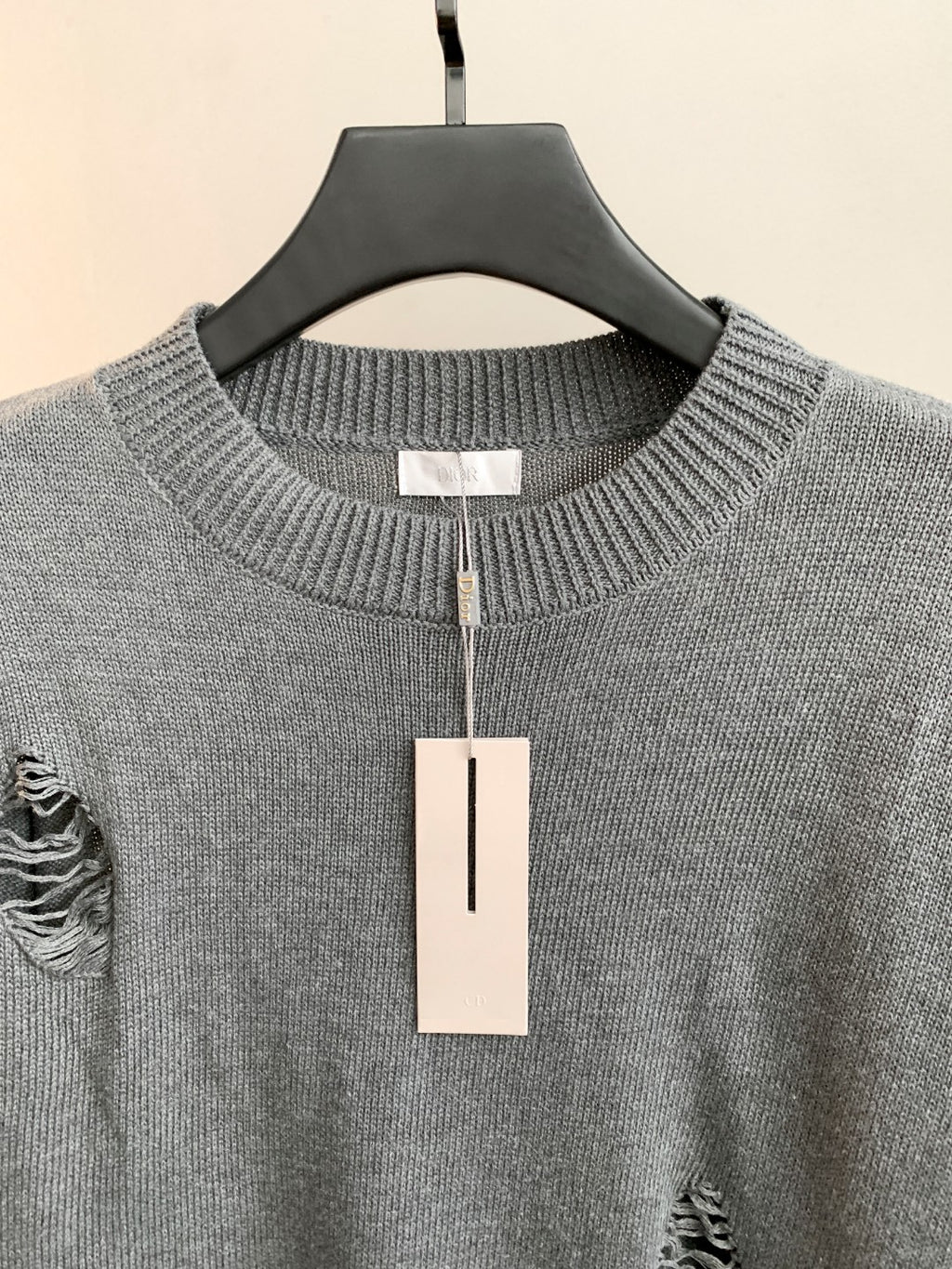 Gray knit sweater close-up: ribbed crew neck and small embroidered left chest