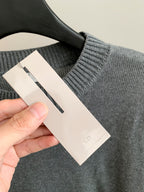 Gray knit sweater tag and ribbed collar on hanger