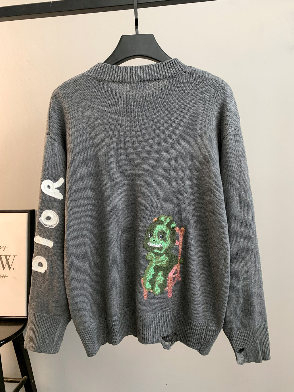 Gray knit sweater with ribbed crew neck and colorful character graphic on back