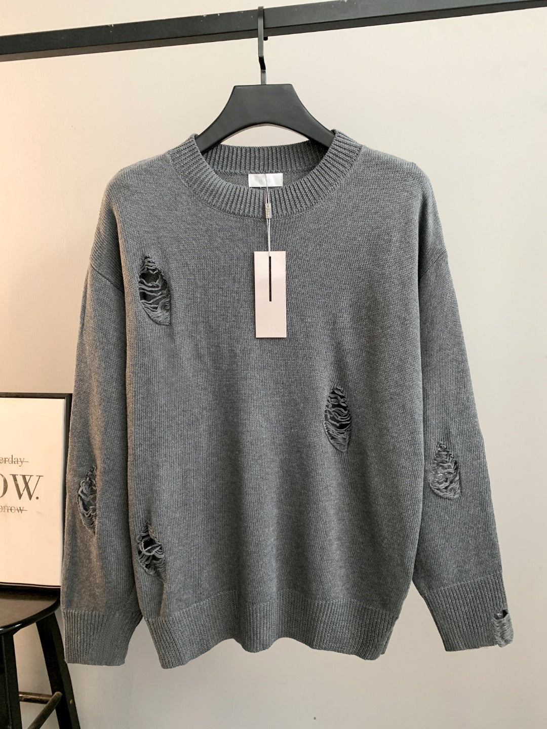 Gray knit sweater with ribbed crew neck and small embroidered motifs on chest