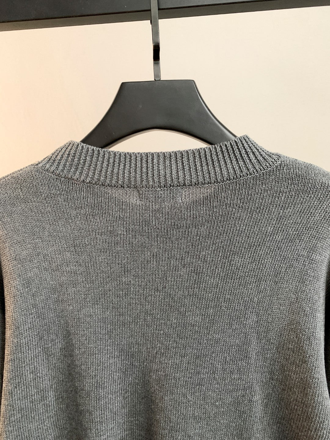 Back view of gray knit sweater with ribbed crew neck and no visible graphics