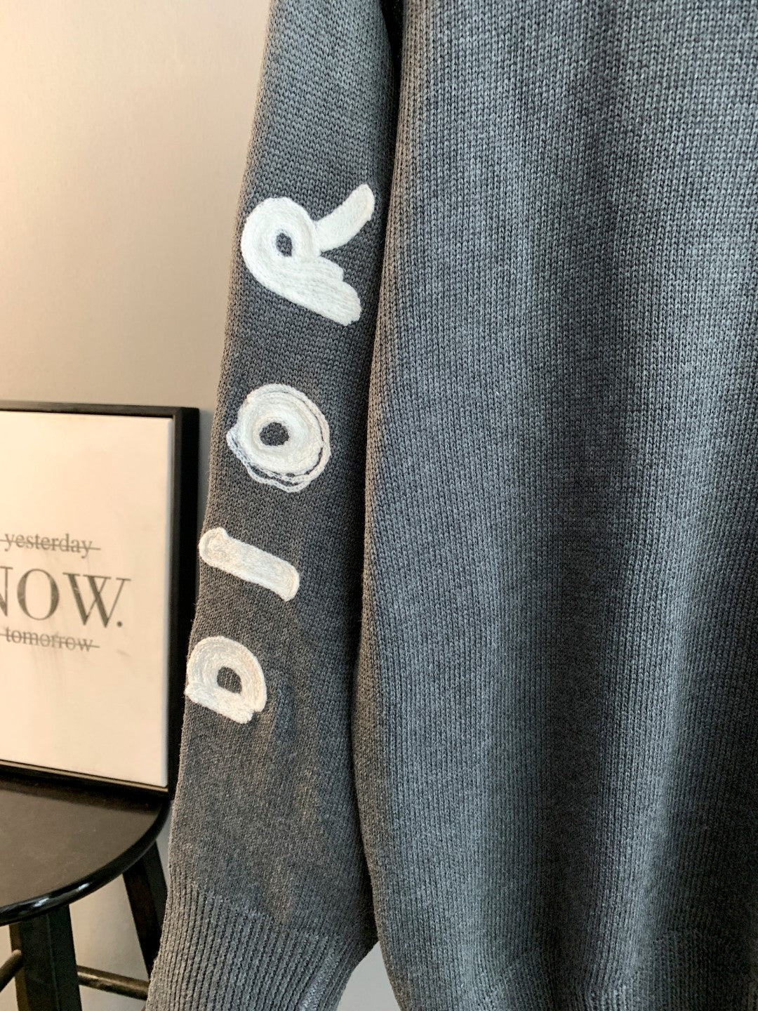Gray knit sweater sleeve with embroidered whale-like icon and ribbed cuff