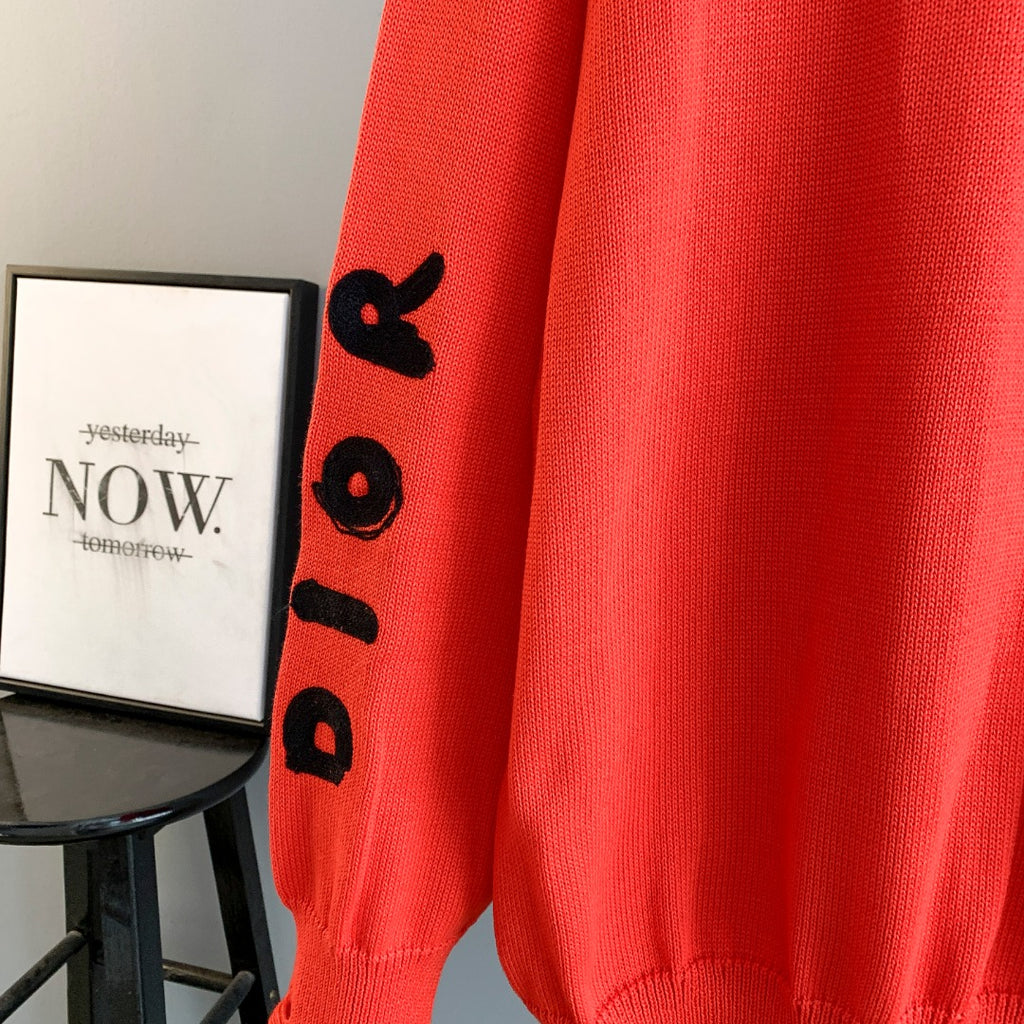 Dior red knit sweater sleeve with black graphic letters and ribbed cuff