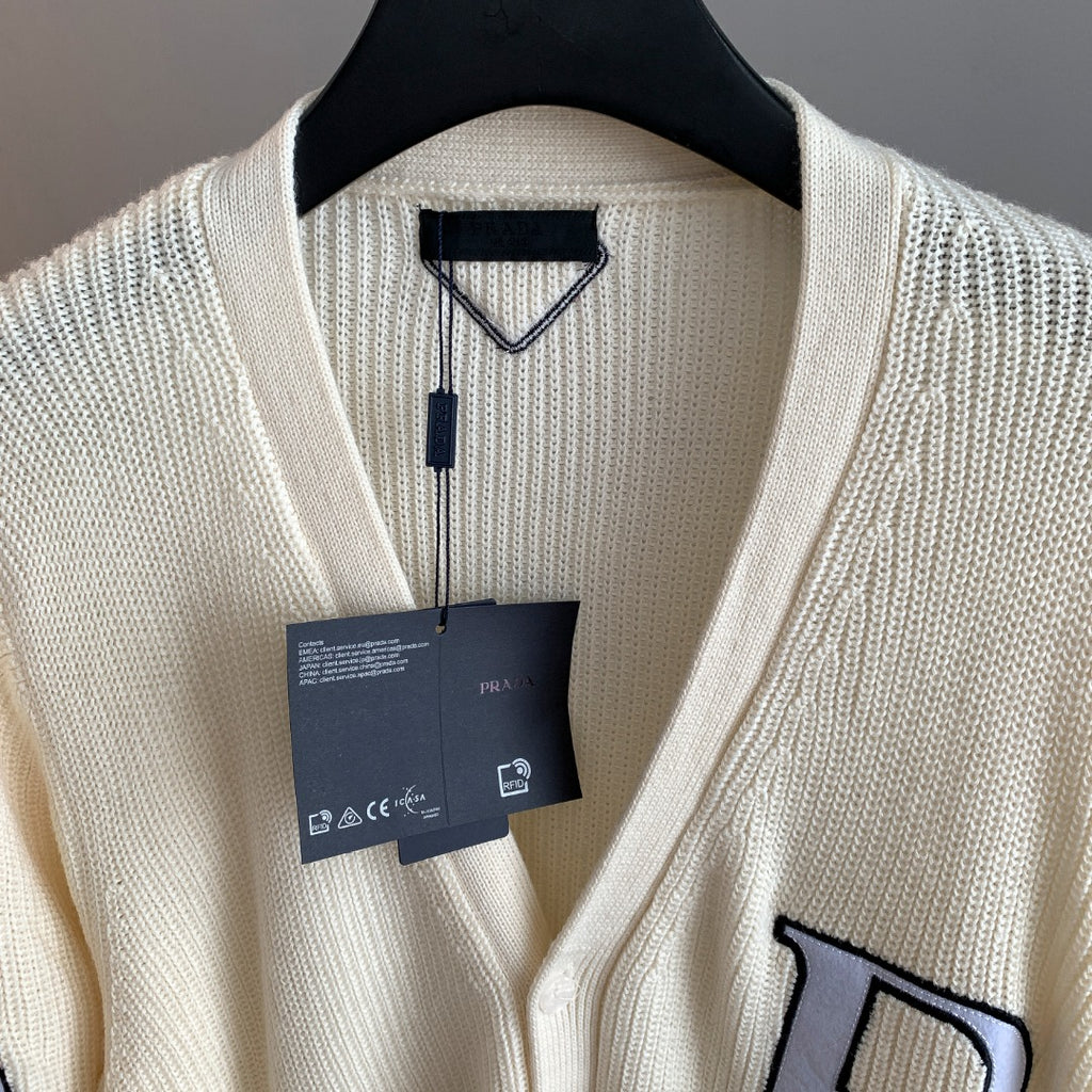 Ivory knit cardigan with V-neck and hanging tag at collar