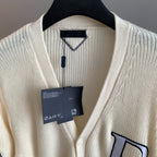 Ivory knit cardigan with V-neck and hanging tag at collar
