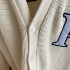 Ivory cardigan front with round buttons and navy embroidered logo panel