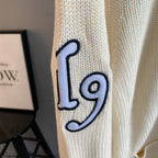 Ivory knit sleeve with navy '19' graphic patch outlined in black