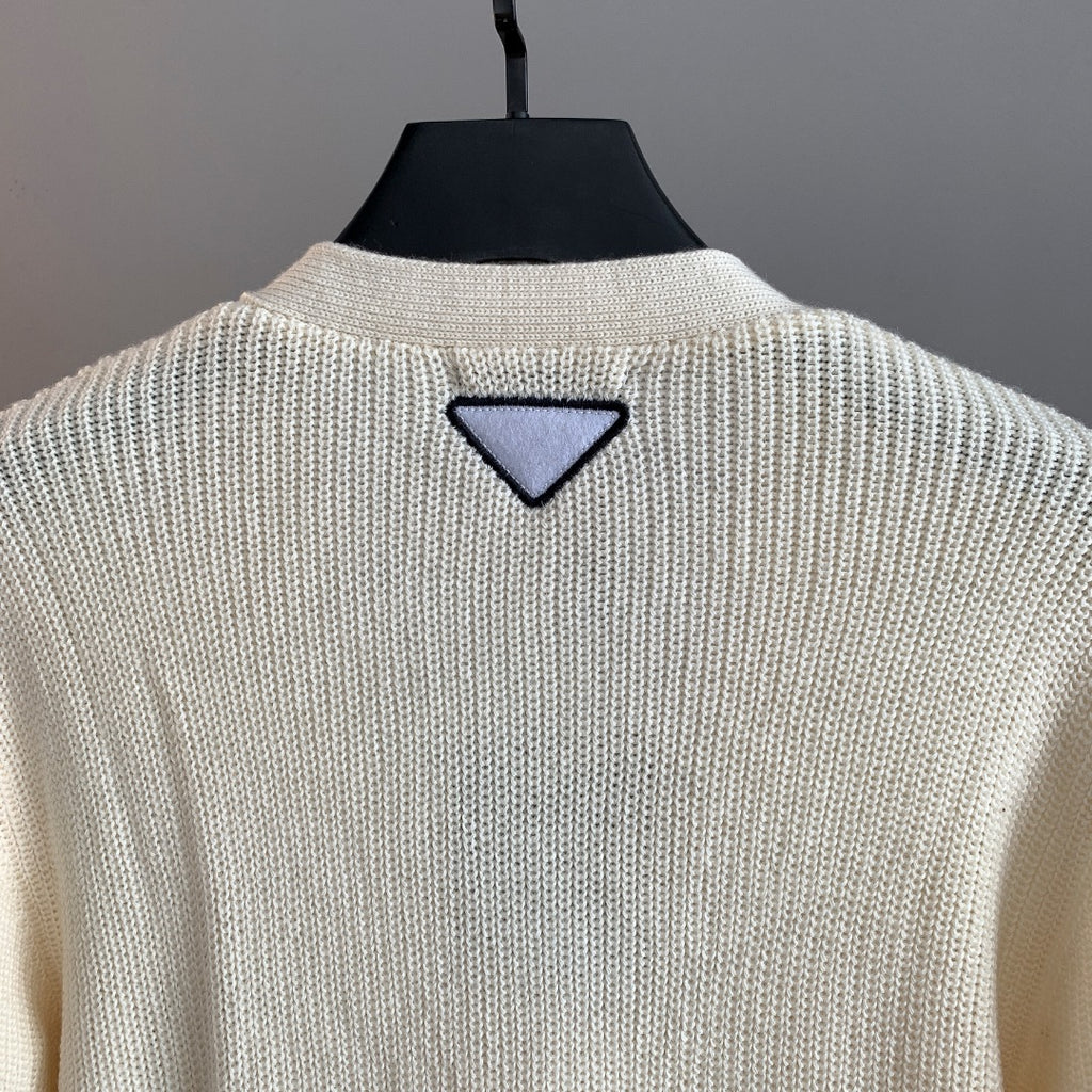 Ivory knit cardigan back with triangular navy appliqué near collar