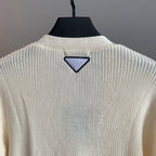 Ivory knit cardigan back with triangular navy appliqué near collar