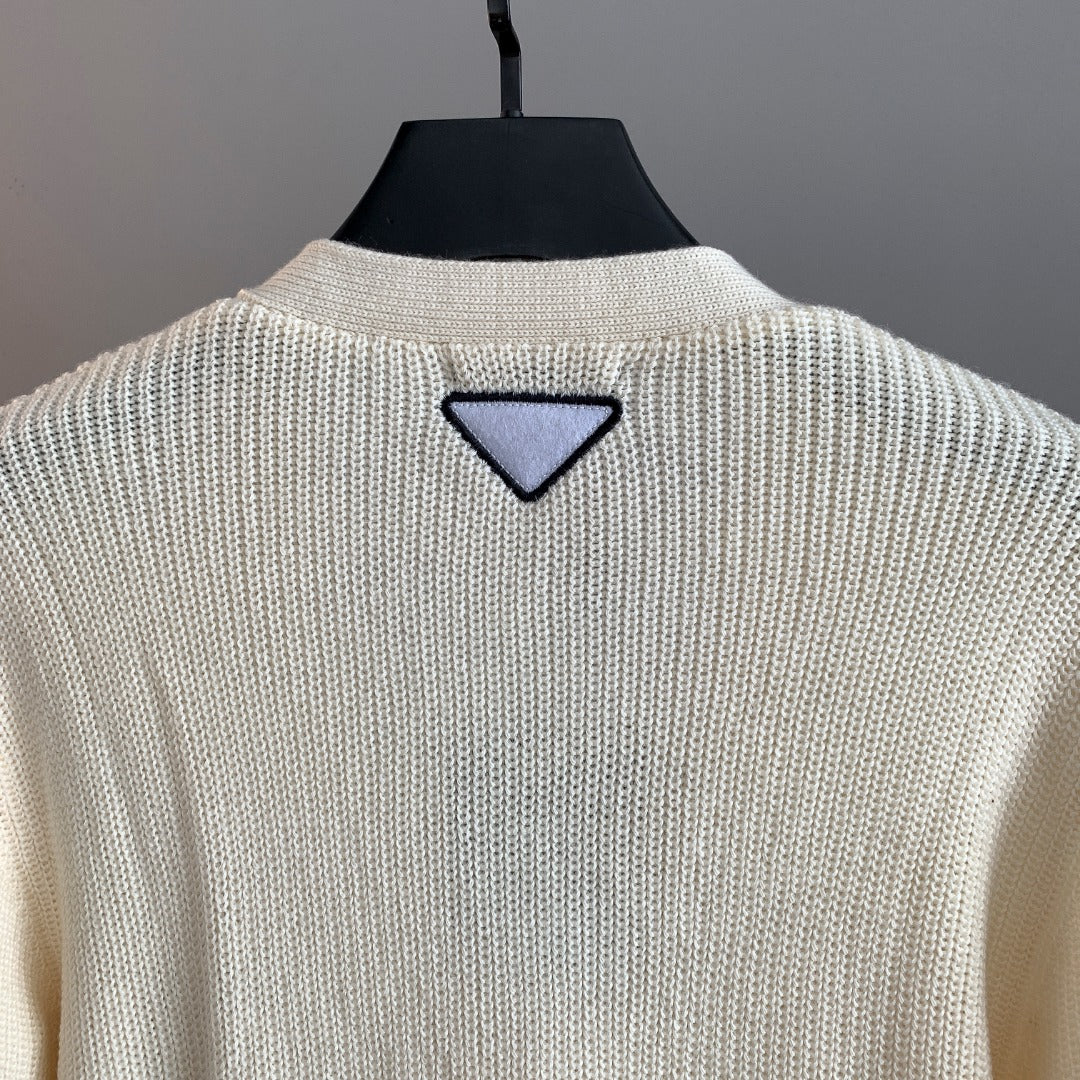 Ivory knit cardigan back with triangular navy appliqué near collar