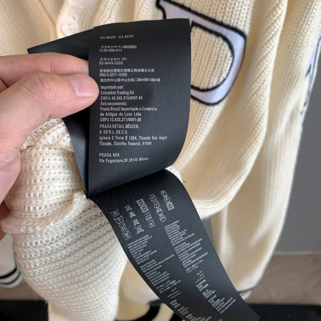 Ivory knit cardigan with hanging care label tags near buttons