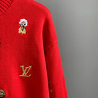 Red sweater detail with embroidered Louis Vuitton emblem and small doll face patch