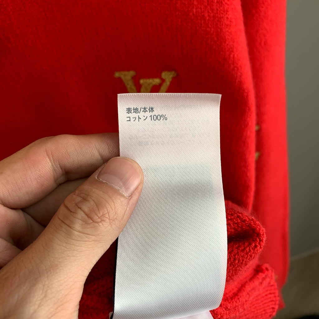 Clothing care label tag reading 100% cotton on red knit sweater