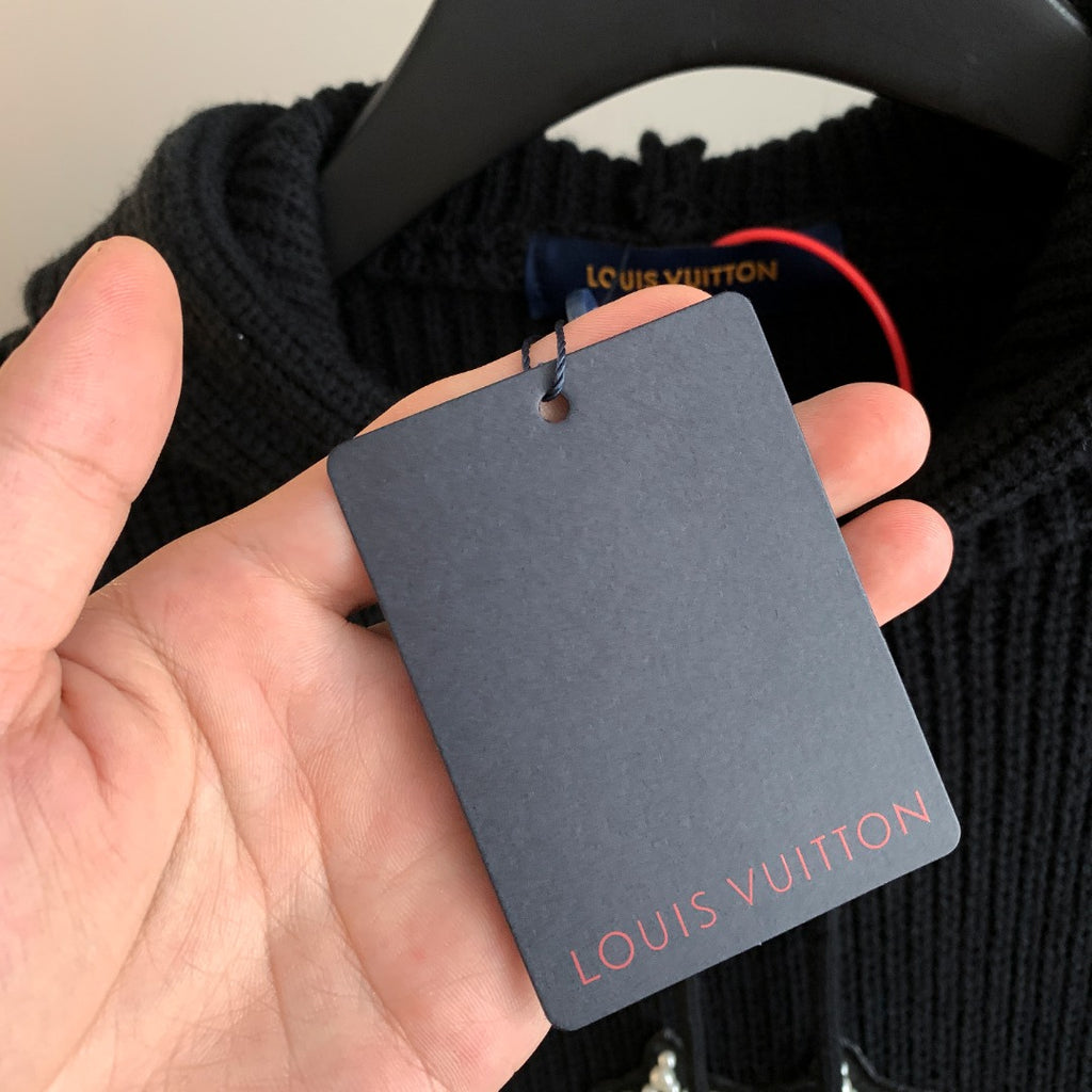 Hooded knit sweater with brand tag held in hand attached to the neckline