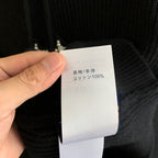 Clothing care label on hooded knit sweater showing fabric content: 100% cotton
