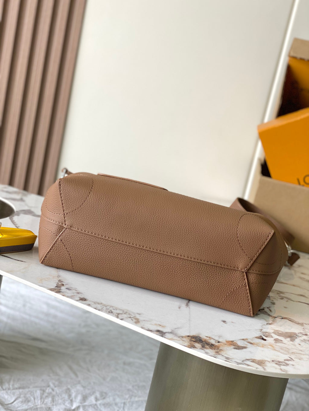 Louis Vuitton tan leather clutch-style bag with long strap and flap closure