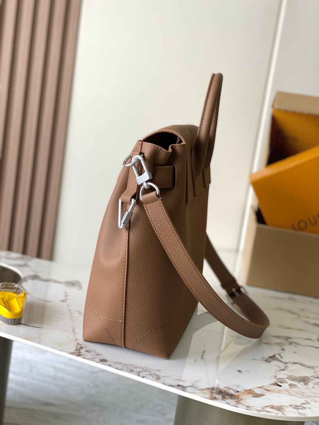 Louis Vuitton tan leather tote bag with shoulder strap and side view of hardware