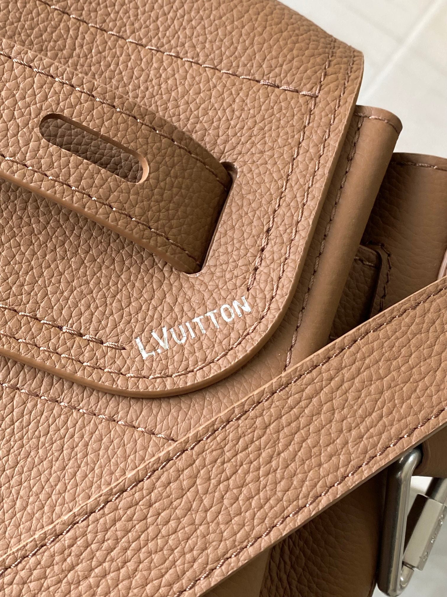 Louis Vuitton tan leather flap with cutout slot and embossed brand lettering