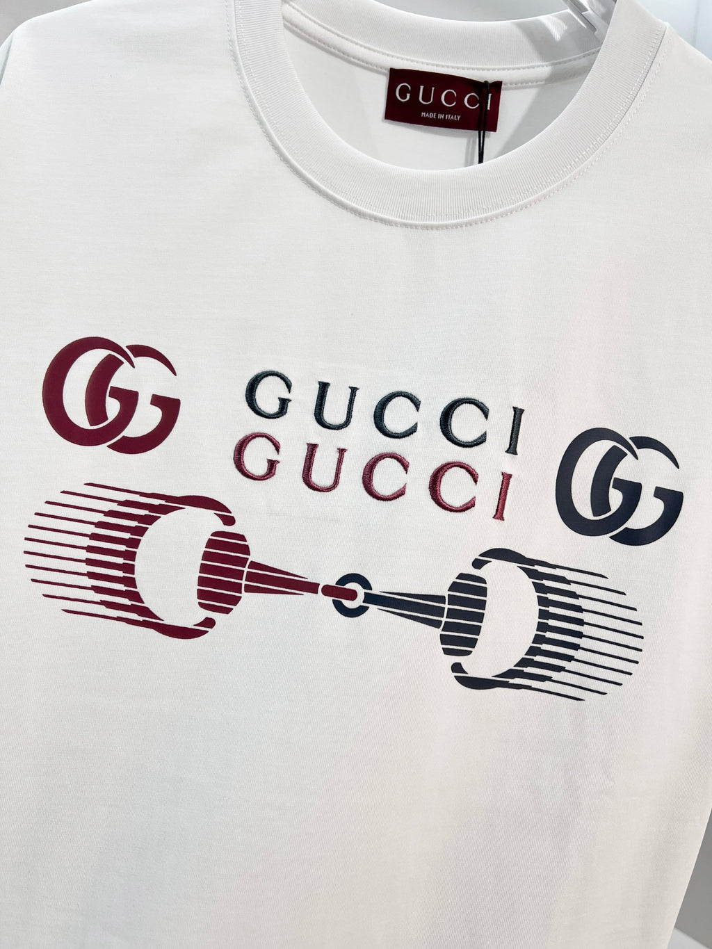 White Gucci crewneck T-shirt with front logo graphic in red and navy, close-up