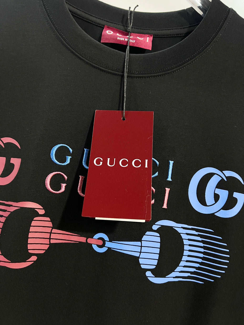 Black Gucci T-shirt neckline and chest graphic with hanging red Gucci tag