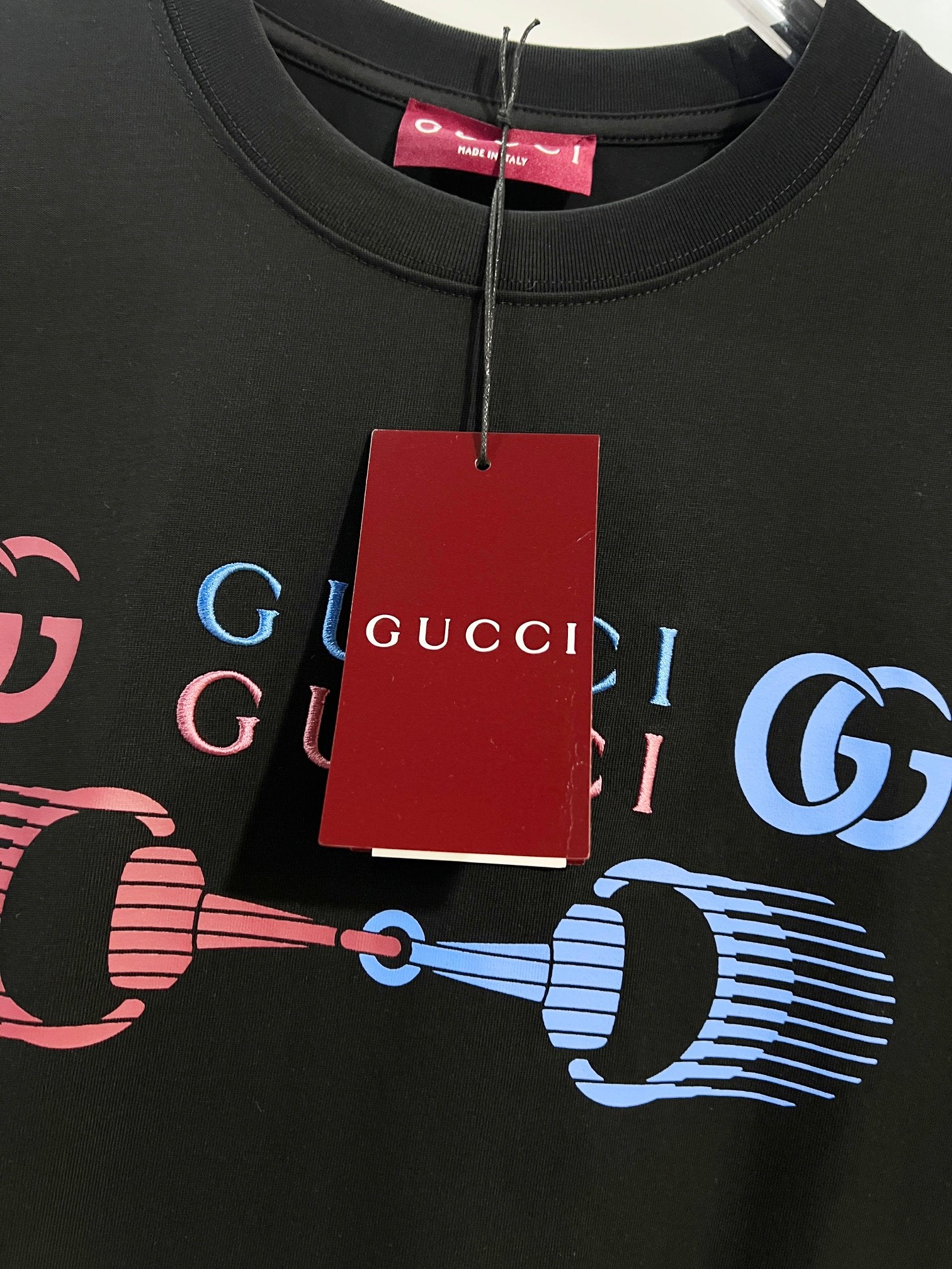 Black Gucci T-shirt neckline and chest graphic with hanging red Gucci tag