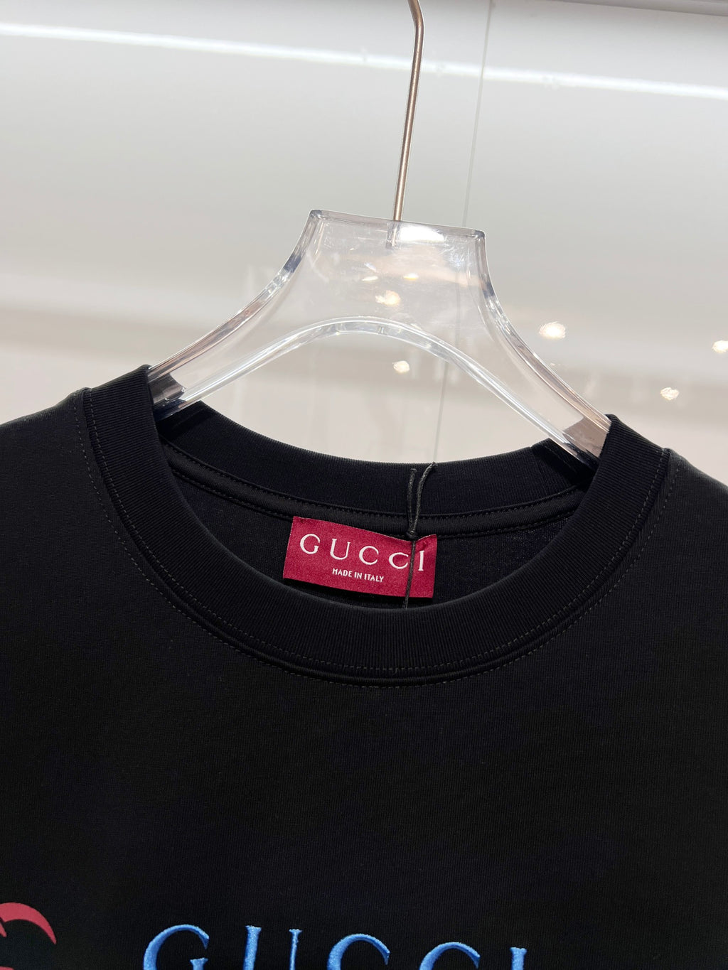 Black Gucci T-shirt close-up of crew neck with red Gucci brand tag