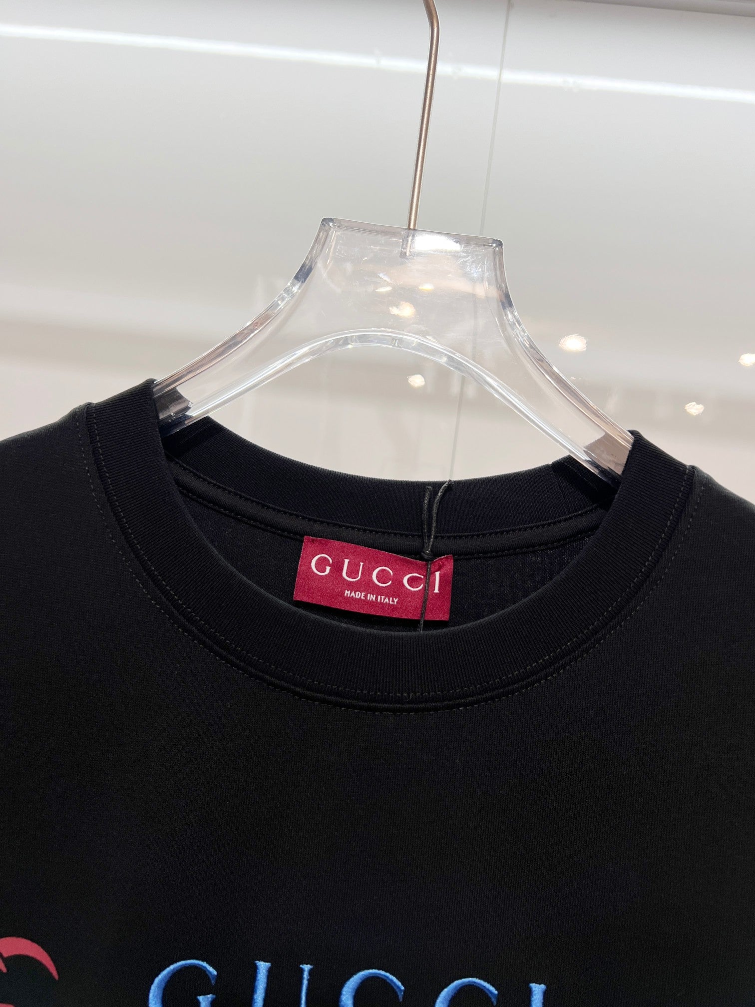 Black Gucci T-shirt close-up of crew neck with red Gucci brand tag