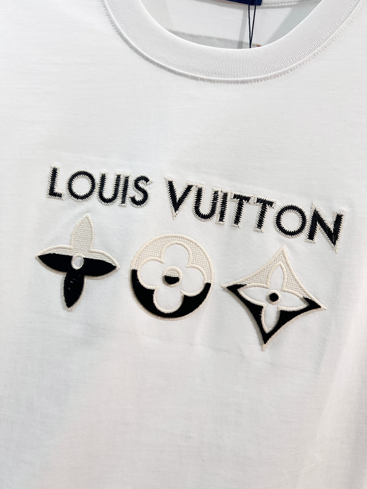 White T-shirt with “LOUIS VUITTON” text and embroidered black icons across chest