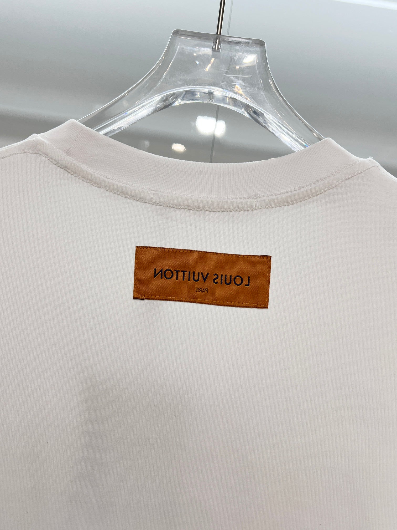 White T-shirt collar close-up with brown brand label at neckline