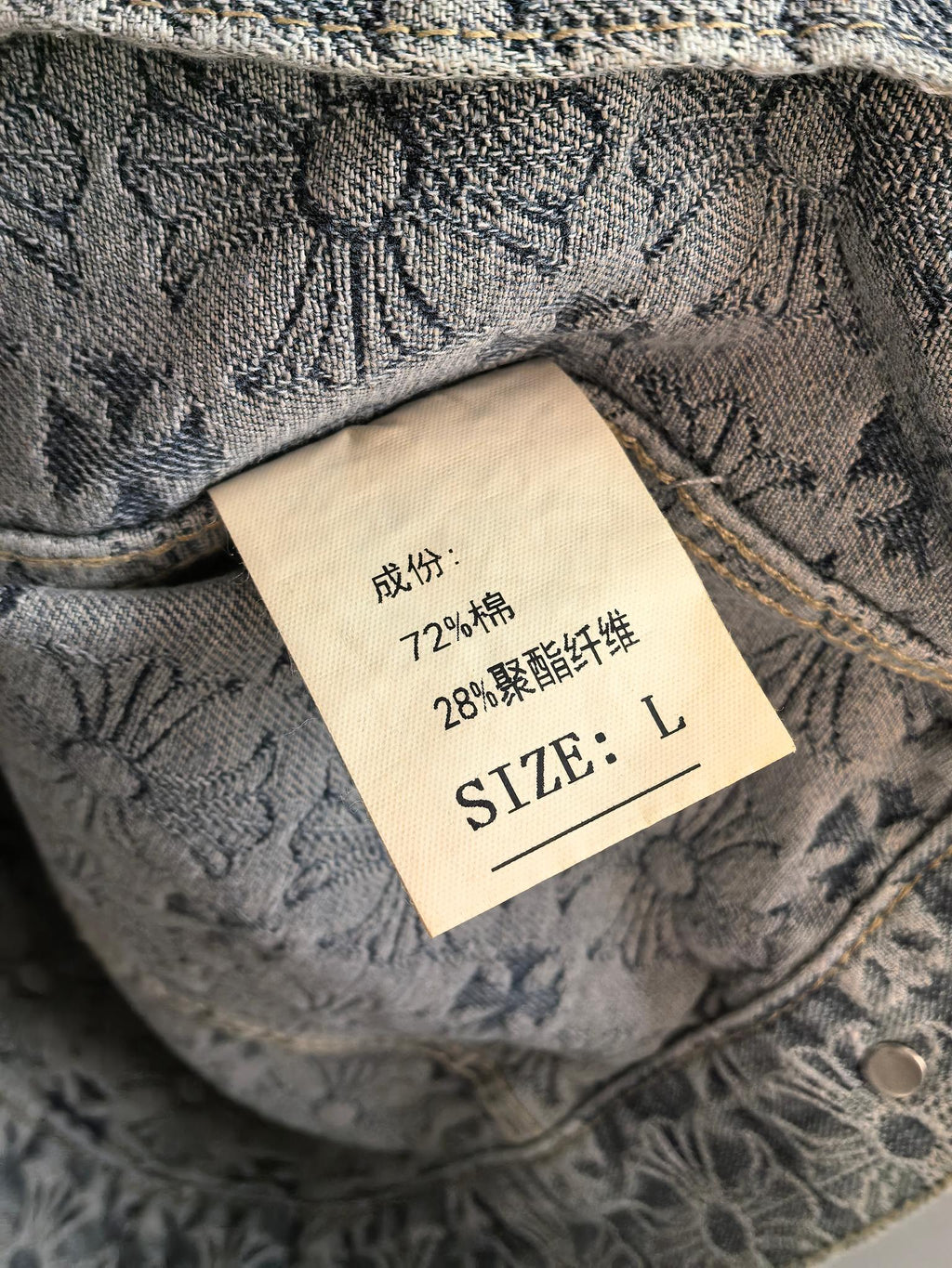 Inside neck label on gray embroidered jacket, size L and care text