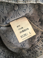 Inside neck label on gray embroidered jacket, size L and care text