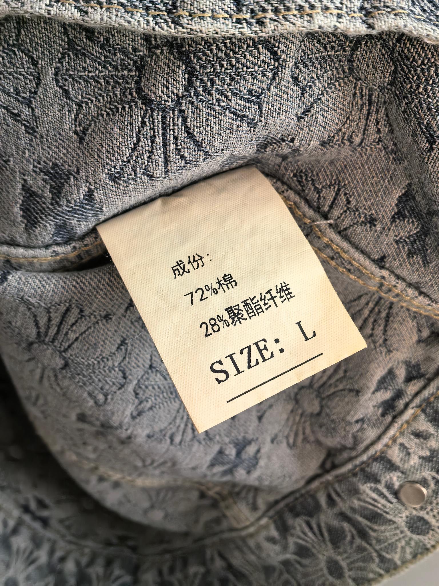 Inside neck label on gray embroidered jacket, size L and care text