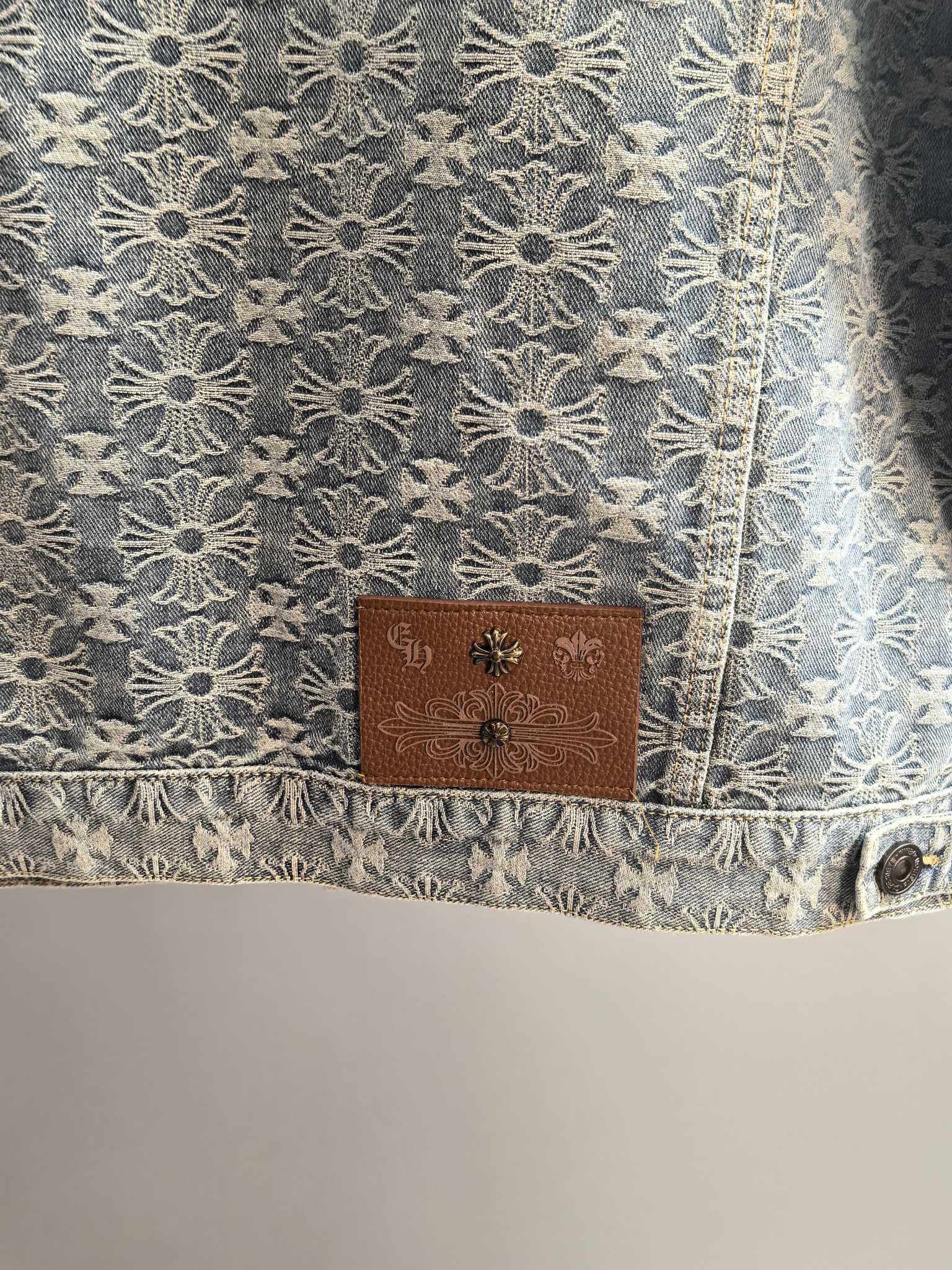 Close-up of gray embroidered jacket hem with brown brand patch and metal button