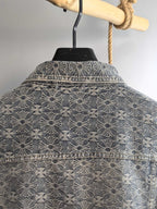 Upper back of gray jacket with embroidered floral pattern and yoke stitching