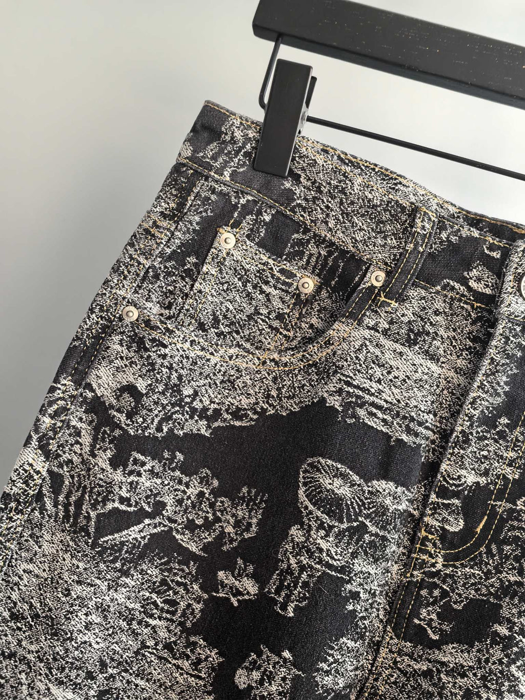 Close-up of black-and-white abstract printed pants front with multiple button pockets