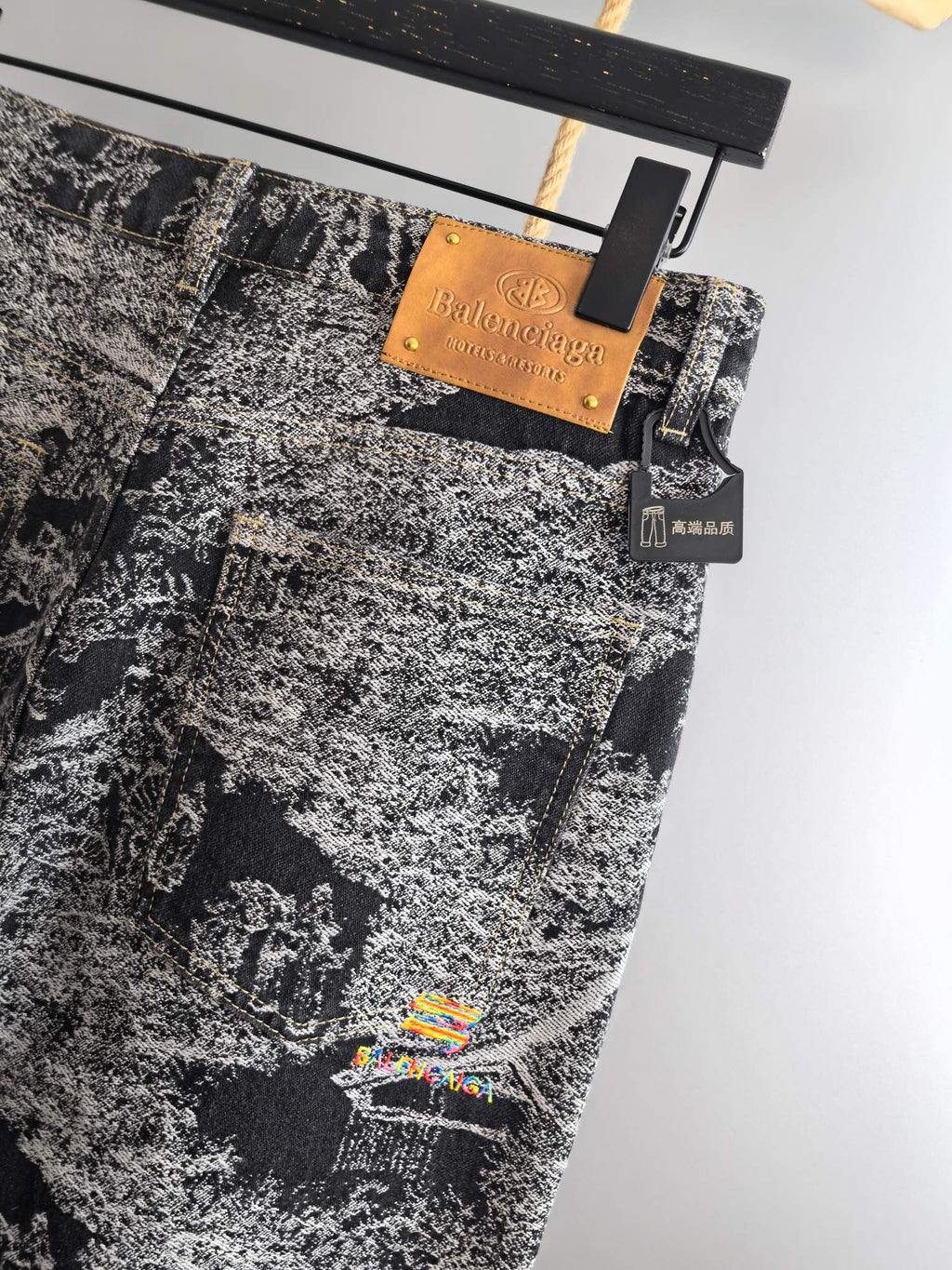 Black-and-white abstract printed pants with tan brand tag and small hanging accessory