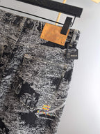 Black-and-white abstract printed pants with tan brand tag and small hanging accessory