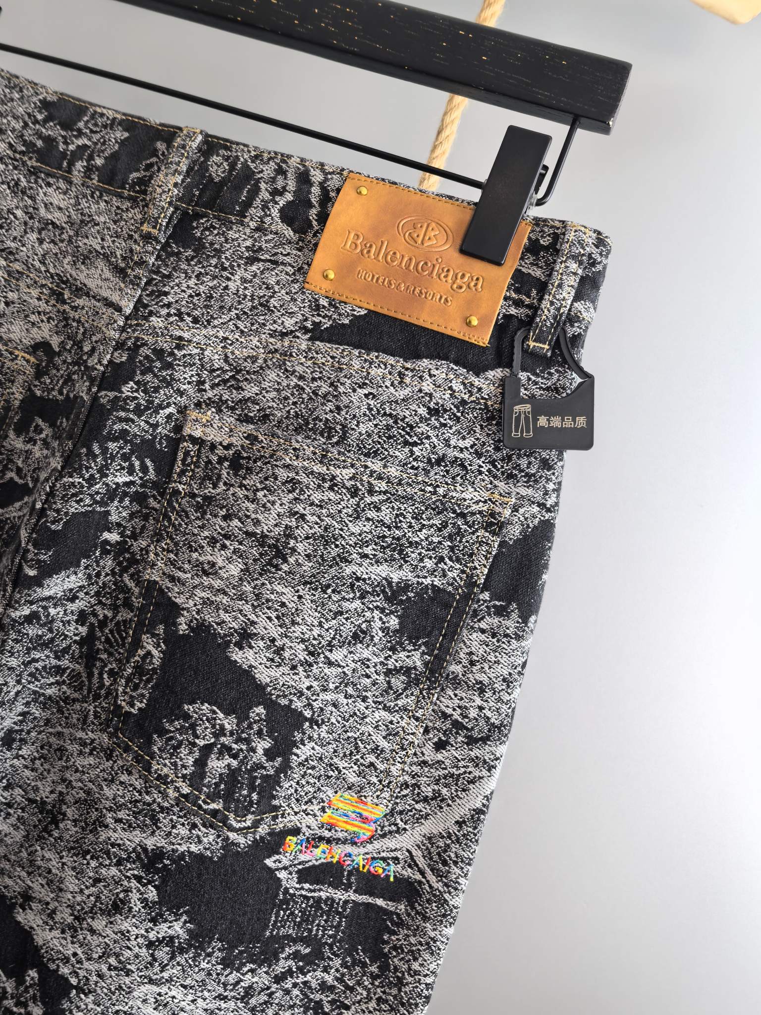 Black-and-white abstract printed pants with tan brand tag and small hanging accessory