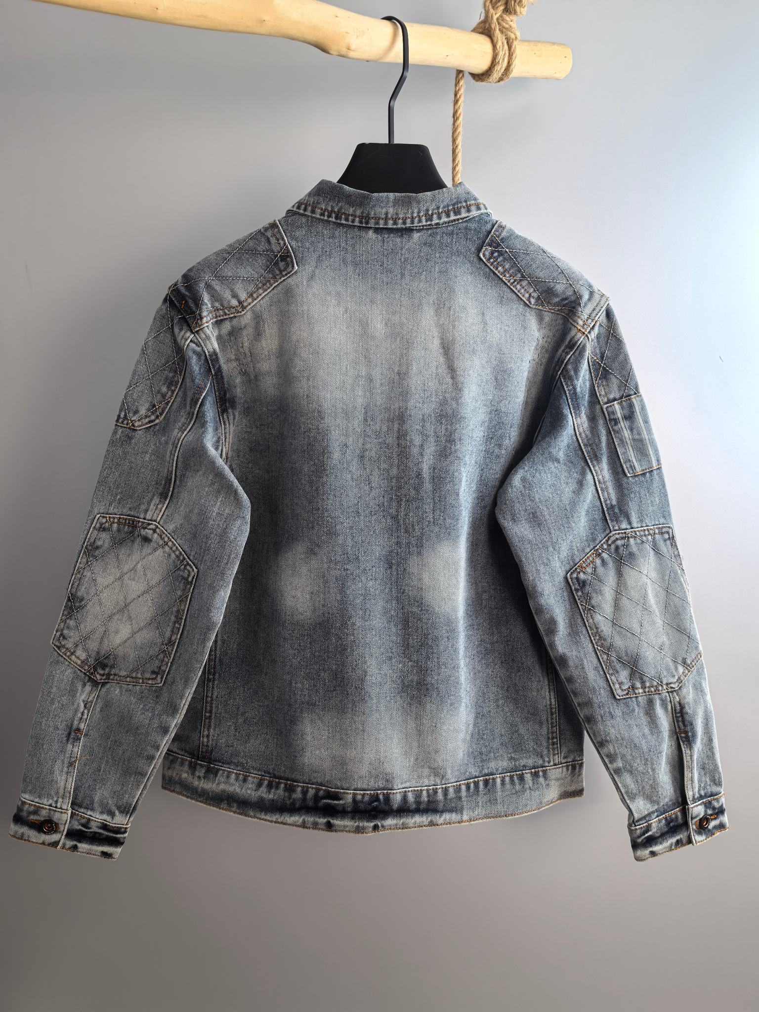 Denim jacket back view with curved yoke seam, light blue wash