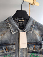 Denim jacket neckline with black Gucci label and chest logo patches