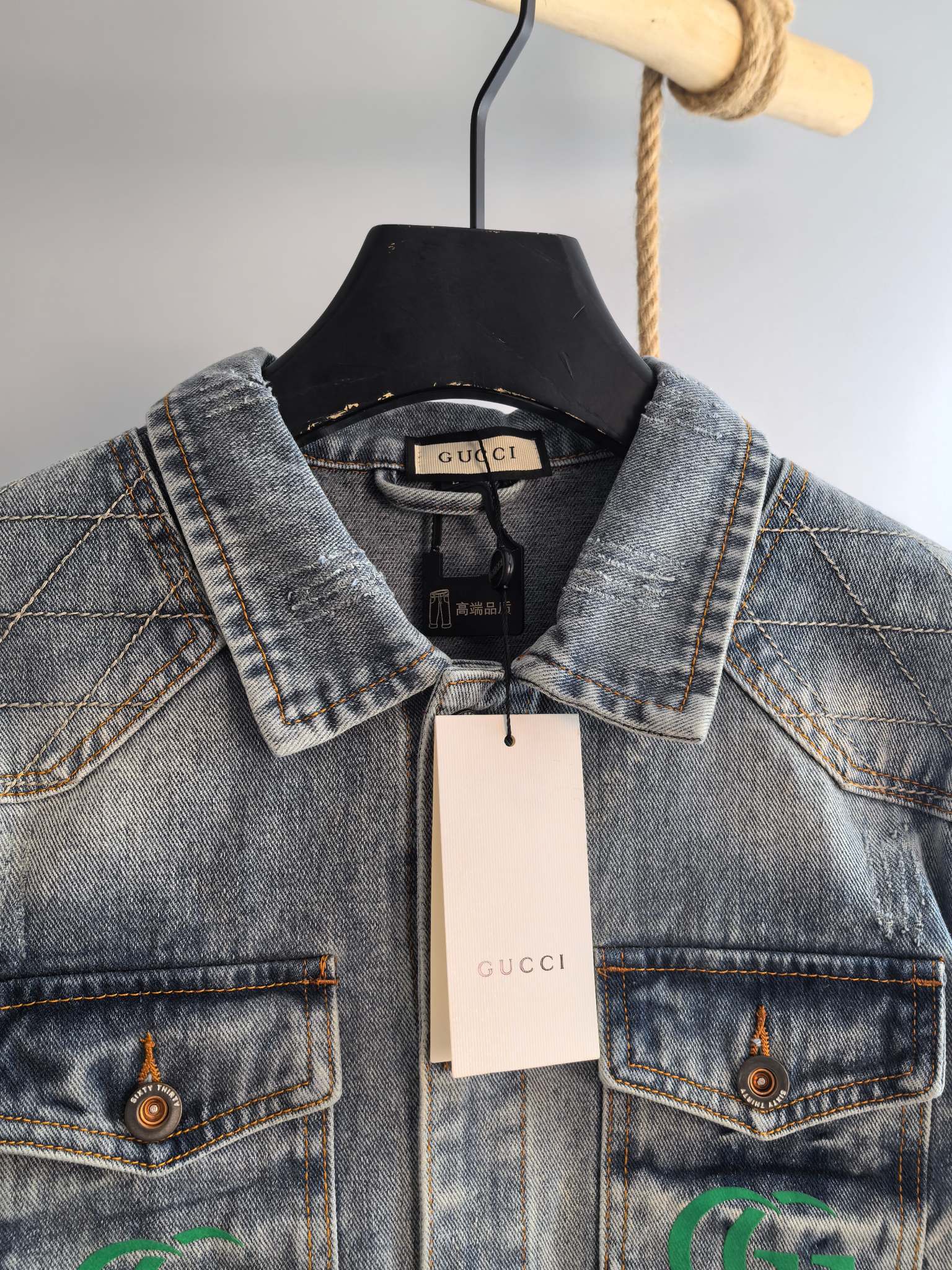 Denim jacket neckline with black Gucci label and chest logo patches