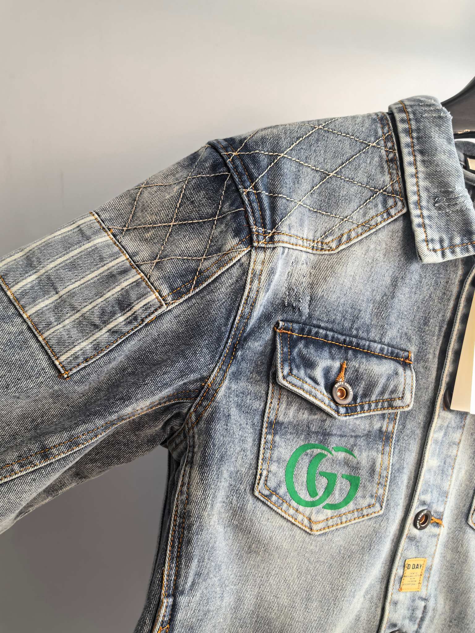 Denim jacket shoulder and front with flap pocket and logo patch, blue wash