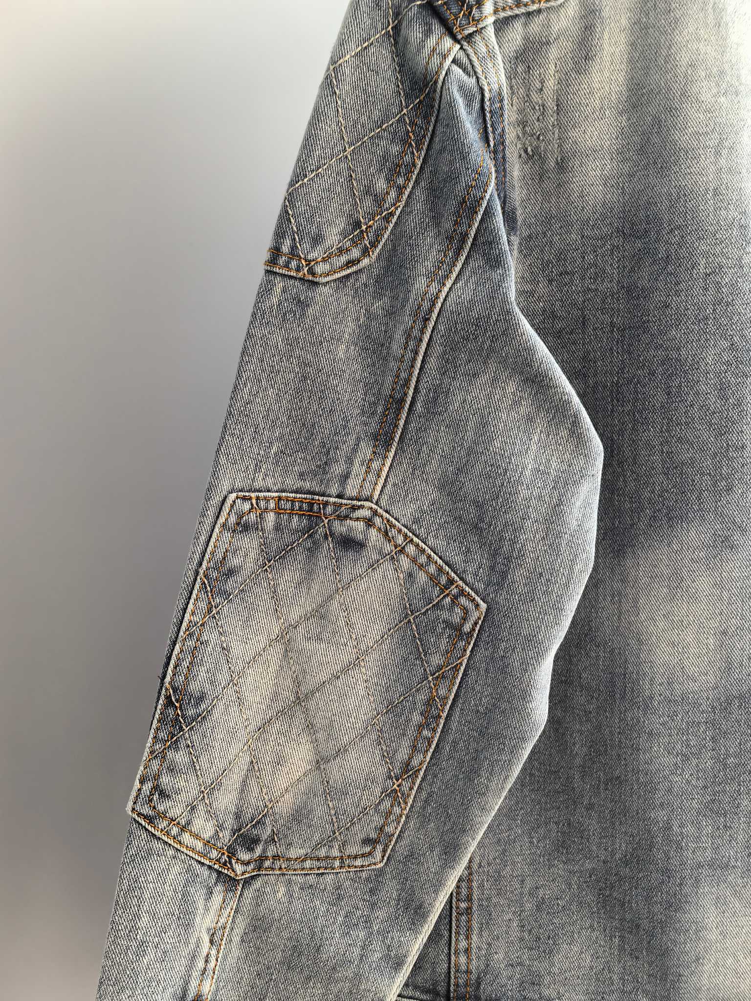 Denim jacket side with quilted patch pocket and stitched seam, light blue wash